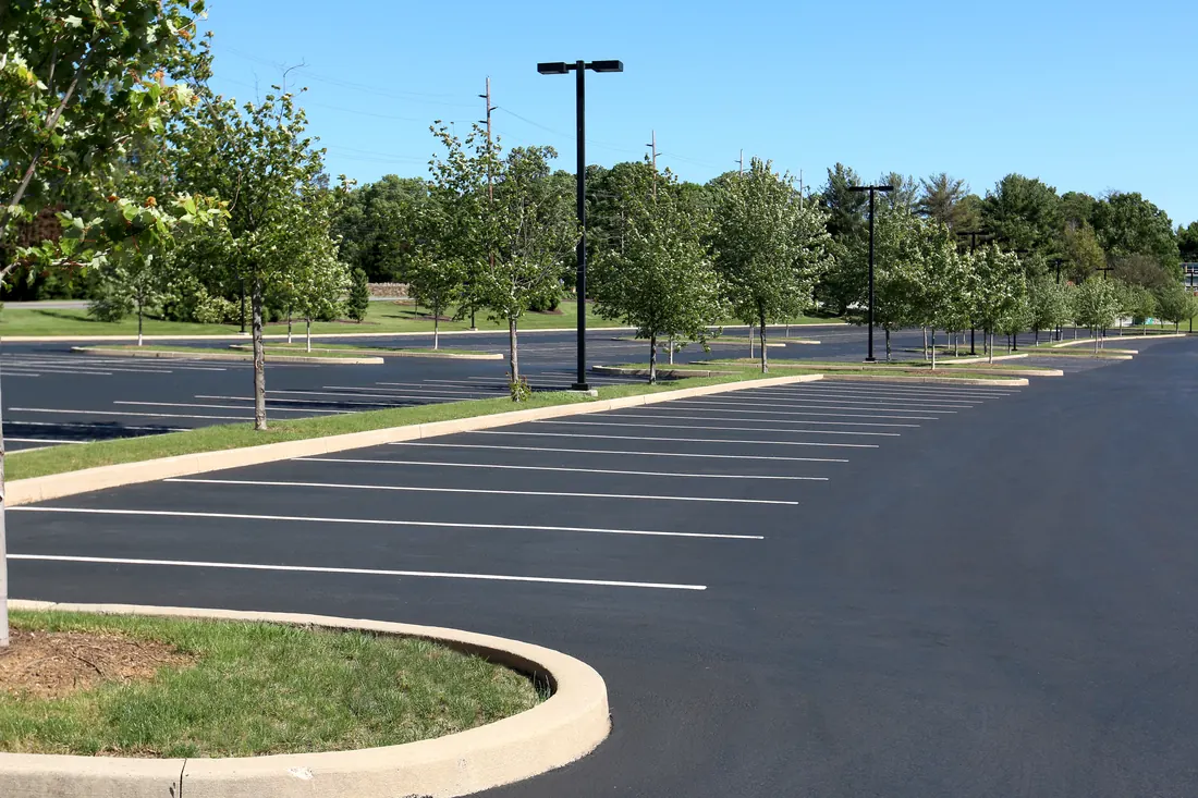 Freshly sealcoated commercial parking lot with crisp white stall lines and clean curbs