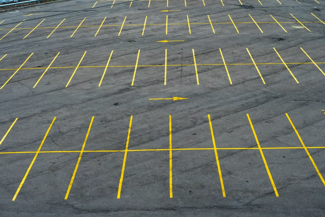 Freshly striped commercial parking lot with bright yellow stall lines and directional arrows on asphalt