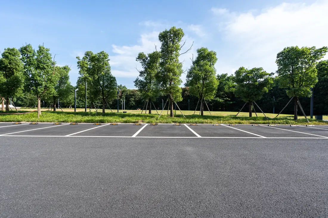 Striped commercial parking stalls with wheel stops on fresh black asphalt