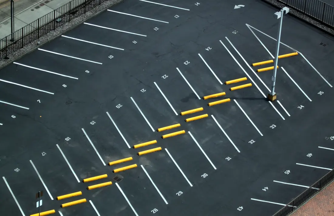 Aerial view of a professionally striped commercial parking lot with numbered stalls and yellow wheel stops